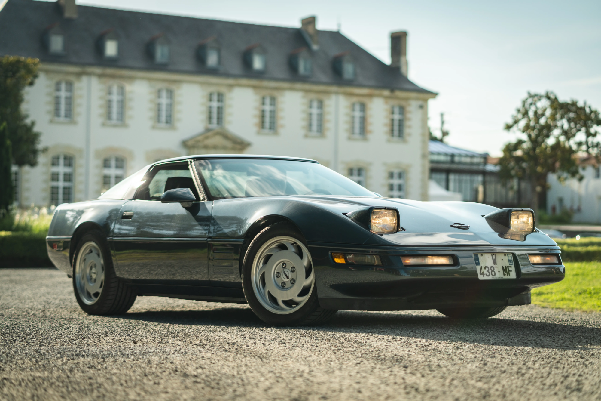 Voiture de collection noire avec phares escamotables garée devant l'abbaye de Villeneuve