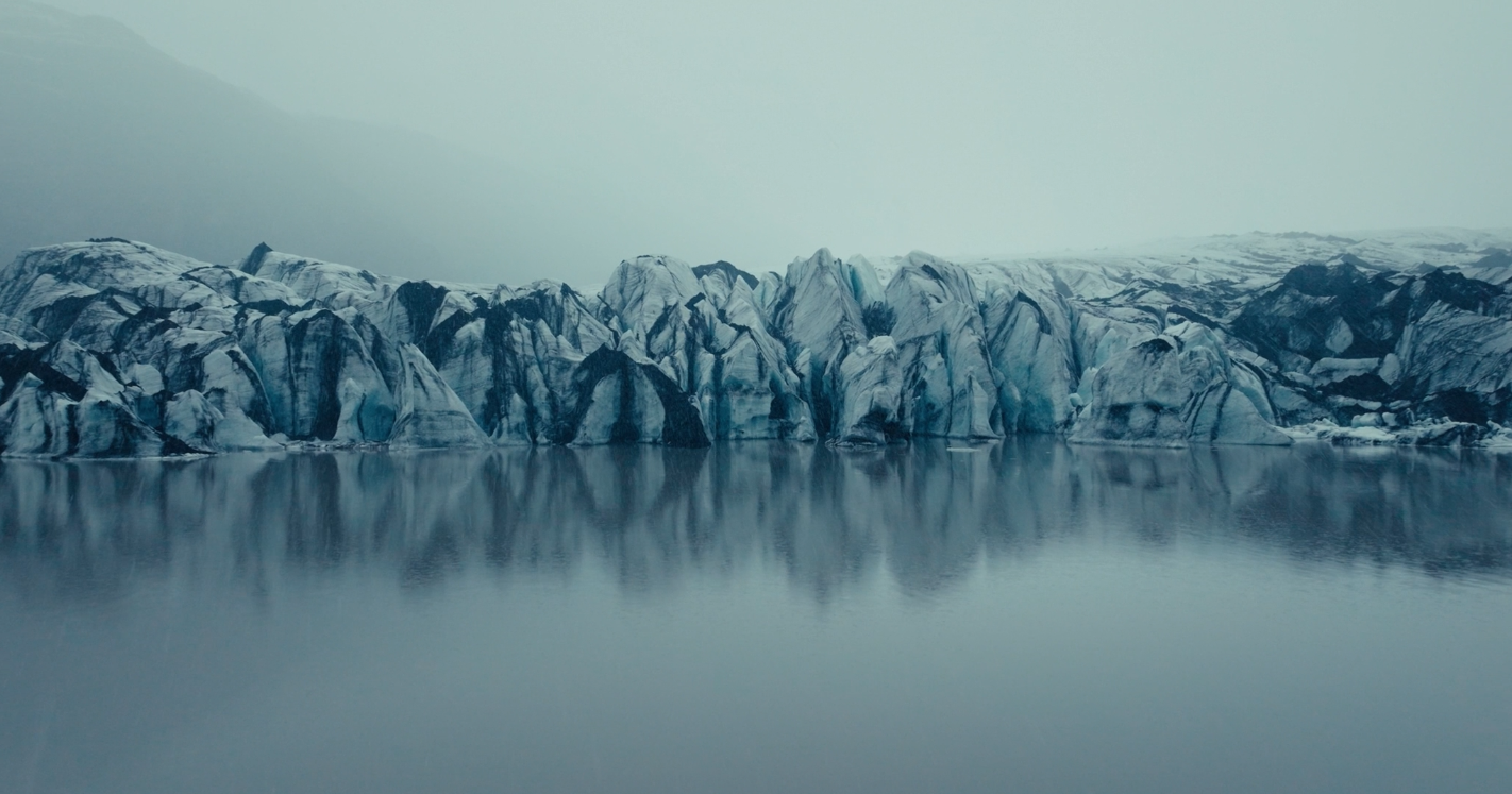 Glacier imposant se reflétant dans une eau calme, ambiance cinématographique froide et bleutée.